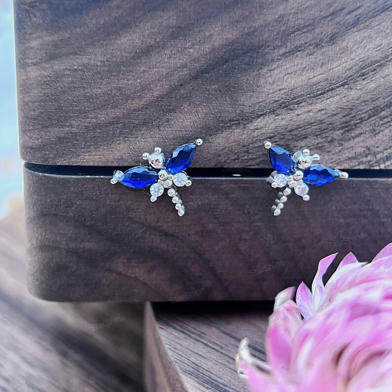 May include: A pair of silver dragonfly earrings with blue and clear crystal accents.