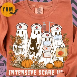 May include: Orange long-sleeve shirt with a Halloween-themed graphic. The design features ghost figures dressed as nurses, pumpkins, flowers, and the text "Intensive Scare Unit". A black cat is also included in the design.
