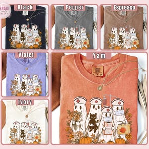May include: A collection of Comfort Colors t-shirts in various colors, including black, pepper, espresso, violet, ivory, and yam. Each shirt features a graphic of ghost nurses with pumpkins and flowers. A gold necklace is included with each shirt.
