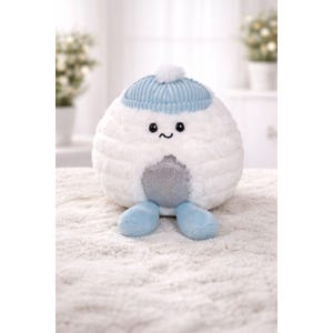 May include: A plush, round, white stuffed toy with a light blue knit cap and matching feet. The toy has a silver belly and a smiling face with black eyes. The hat has a white pom-pom on top. The toy is on a white, textured surface.