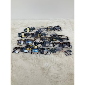 May include: A selection of spectacles with diverse frame designs and hues, such as black, brown, and tortoiseshell. The glasses are presented on a white, textured surface, each with a price tag attached.