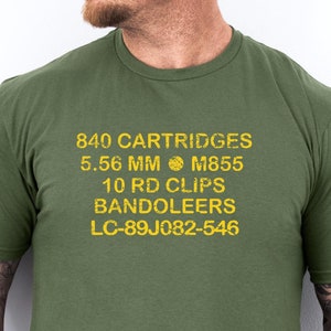 May include: A green t-shirt with the text "840 CARTRIDGES 5.56 MM M855 10 RD CLIPS BANDOLEERS LC-89J082-546" printed in yellow.