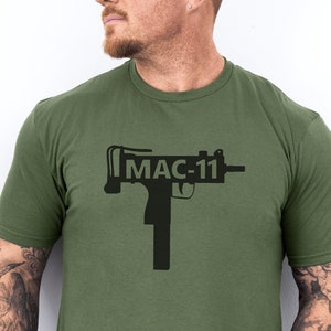 May include: A green t-shirt with a black silhouette of a MAC-11 submachine gun and the text "MAC-11" printed on the front.