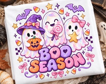Op de afbeelding: Een wit t-shirt met een kleurrijke afbeelding van drie schattige spookjes. Eén spookje draagt een paarse heksenhoed en houdt een pompoen vast, een ander houdt een roze lolly vast en de derde houdt een gele ster vast. De tekst BOO SEASON staat eronder.