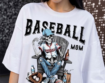 May include: White t-shirt with a graphic of a skeleton baseball player wearing a baseball cap, jersey, and ripped jeans, seated in a wooden chair. The text "BASEBALL MOM" is above the graphic.