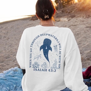 May include: White sweatshirt with a blue graphic of a whale shark, starfish, jellyfish, and other sea creatures. The text reads "When you go through deepwaters, I will be with you" and "Isaiah 43:2".