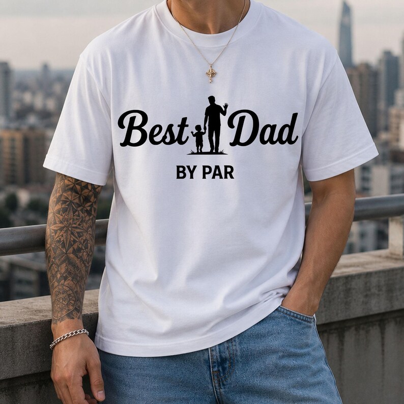May include: White t-shirt with the text "Best Dad" in a cursive font, accompanied by a silhouette of a father and child. Below the text is "BY PAR" in a sans-serif font. The shirt is a casual style.
