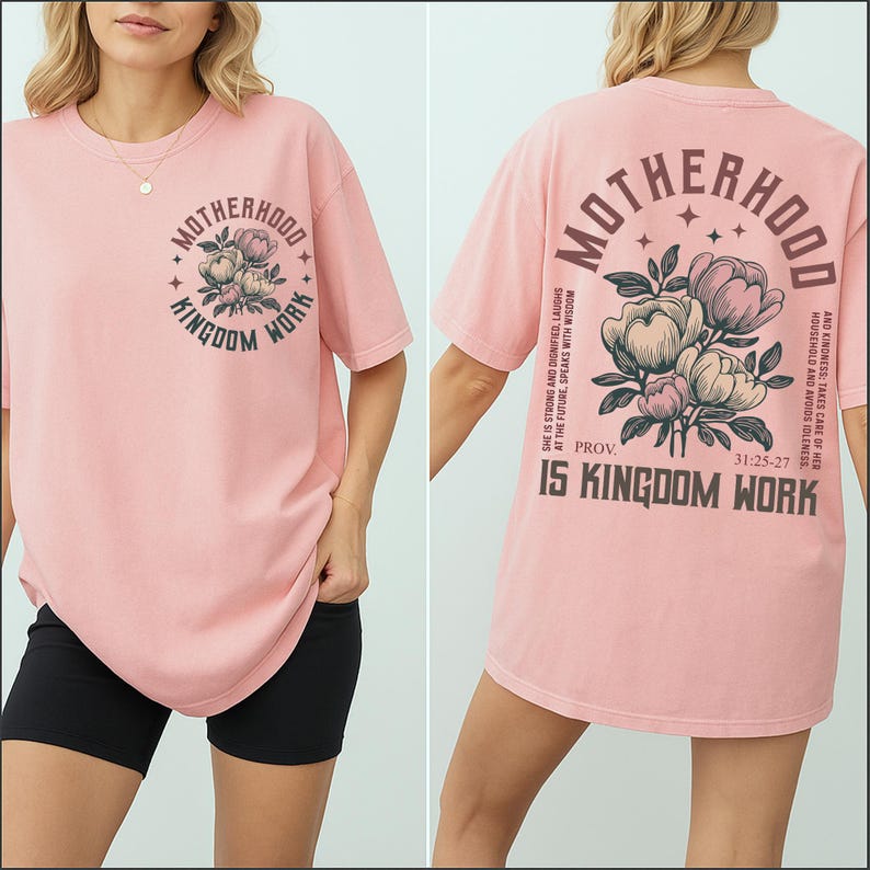 May include: A light pink t-shirt with the text "Motherhood Kingdom Work" and a floral design on the front. The back of the shirt features the same text and design, along with additional text from Proverbs 31:25-27.