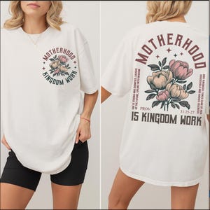 May include: Off-white t-shirt with a floral design and the words "Motherhood Kingdom Work" in a circular design on the front. The back of the shirt features the words "Motherhood" and "Kingdom Work" with a floral design and a Bible verse.
