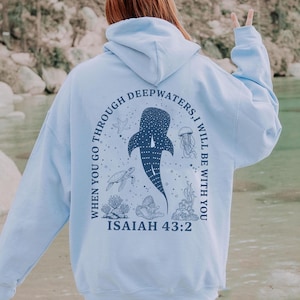 May include: Light blue hoodie with a marine life design. The back features a whale shark, jellyfish, and turtle, with the text "WHEN YOU GO THROUGH DEEPWATERS, I WILL BE WITH YOU" and "ISAIAH 43:2" in dark blue.