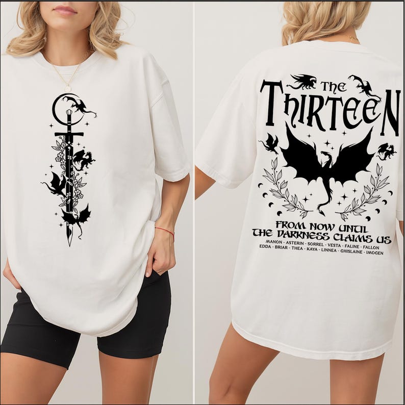 May include: White t-shirt featuring a black graphic of a sword, dragons, and floral elements on the front. The back of the shirt displays the text "The Thirteen" and "From now until the darkness claims us" with dragon and floral designs.