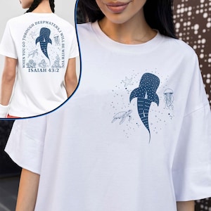 May include: White t-shirt with a blue whale shark design and the text "WHEN YOU GO THROUGH DEEPWATERS, I WILL BE WITH YOU ISAIAH 43:2". The shirt features a whale shark, turtle, starfish, and jellyfish illustrations.