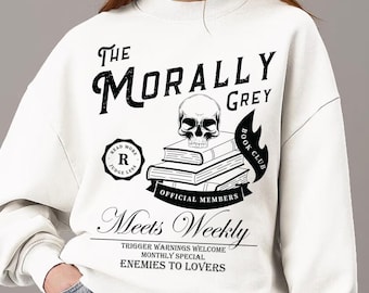 May include: White sweatshirt with a black graphic design. The design includes the text "The Morally Grey Book Club" with a skull on top of books. Additional text includes "Official Members" and "Meets Weekly".