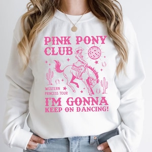 May include: White sweatshirt with a pink graphic. The graphic features the text "PINK PONY CLUB" and "I'M GONNA KEEP ON DANCING!" along with a cowgirl riding a horse, a disco ball, cacti, and horseshoes.