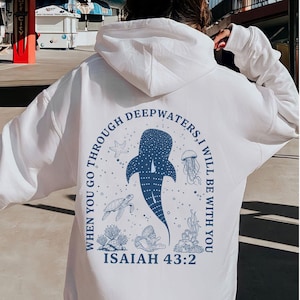 May include: White hoodie with a blue graphic on the back. The graphic features a whale shark, starfish, jellyfish, turtle, and coral, with the text "WHEN YOU GO THROUGH DEEPWATERS, I WILL BE WITH YOU" and "ISAIAH 43:2".