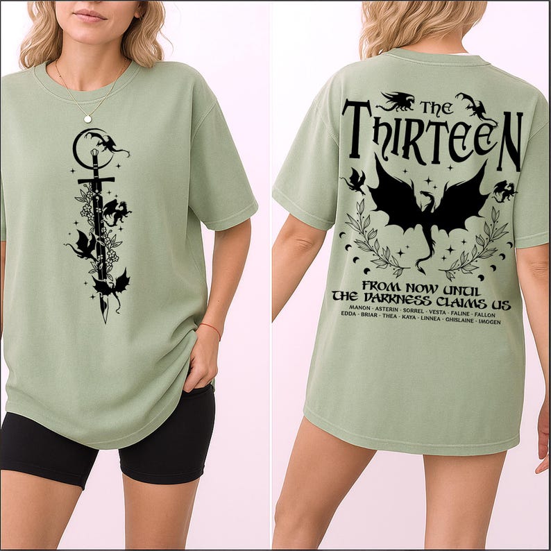 May include: Sage green t-shirt with a black graphic of a sword, dragons, and floral elements on the front. The back features the text "The Thirteen" and "From Now Until The Darkness Claims Us" with a dragon illustration.