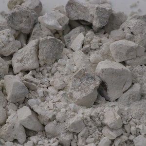 May include: A close-up of a pile of white, broken, and powdered rocks. The rocks are of various sizes and shapes.