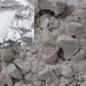 May include: Close-up of white chalk in both powdered and chunk forms. The chalk is a light gray color and has a rough texture.