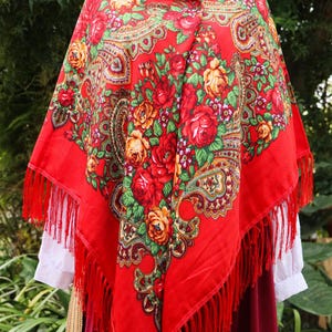 以下が含まれることがあります： 花柄とフリンジが付いた赤いショール。ショールは柔らかく軽量な生地で作られており、ペイズリー柄が特徴です。