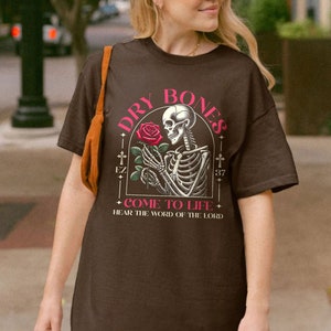 May include: Brown t-shirt with a graphic of a skeleton holding a rose and the text "Dry Bones Come to Life Hear the Word of the Lord"