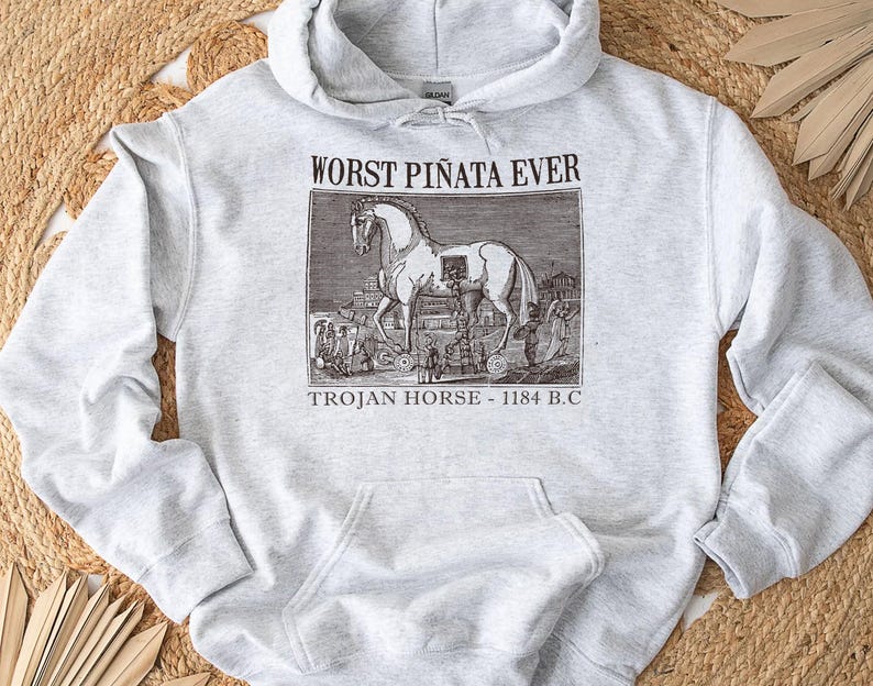 May include: Light gray hoodie with a front pocket and drawstring hood. The graphic on the front features a black and white illustration of the Trojan Horse with the text "WORST PI&Ntilde;ATA EVER" and "TROJAN HORSE - 1184 B.C."