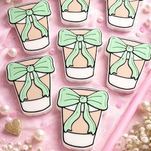 Puede incluir: Una taza de cerámica blanca con un asa negra y el texto "But First, Coffee" en negro y negrita. La taza está sobre una superficie blanca.