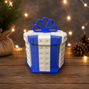 May include: A blue and white gift box container with a bow on top. The box features a geometric design with vertical white panels accented by circular indentations resembling screw heads, contrasting against solid blue side panels and a blue bow.