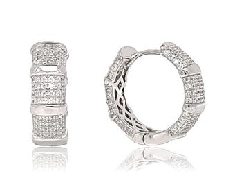 May include: A pair of silver hoop earrings with a pave setting of clear cubic zirconia stones. The earrings are approximately 1 inch in diameter.