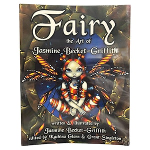 Puede incluir: Una portada de libro con el título "Fairy" y el subtítulo "the Art of Jasmine Becket-Griffith". La portada muestra un hada con grandes ojos azules, pelo rojo y alas de mariposa. El libro está escrito e ilustrado por Jasmine Becket-Griffith.
