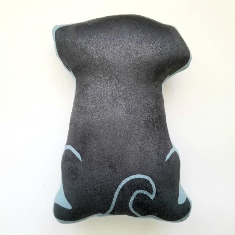 Puede incluir: Almohada de perro de felpa negra con detalles de contorno azul. La almohada tiene forma de perro sentado con la cola enroscada.