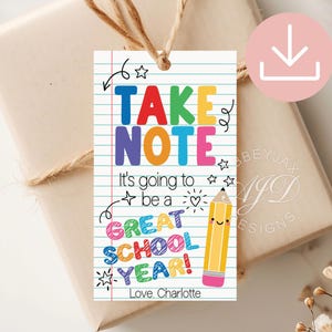 Könnte beinhalten: Ein rechteckiges Geschenkanhänger mit weißem Hintergrund und blauen horizontalen Linien wie auf Notizpapier. Der Text lautet TAKE NOTE It's going to be a GREAT SCHOOL YEAR! Love, Charlotte. Ein gelber Bleistift mit Gesicht und Radiergummi ist abgebildet.
