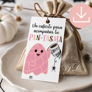 May include: A rectangular white gift tag featuring a pink ghost-shaped bread illustration holding a coffee mug with the text "¡BUU!". The tag includes the text "Un cafecito para acompañar tu PAN-TASMA" and "DE:" at the bottom, tied to a small burlap bag.
