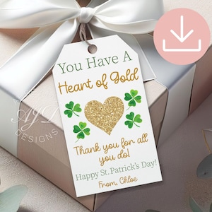 May include: A gift tag with the text "You Have A Heart of Gold" and "Happy St. Patrick's Day!" features a gold glitter heart and green shamrocks. The tag is attached to a wrapped gift with a white ribbon.