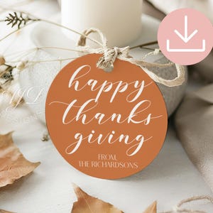 May include: A round, orange gift tag with the words "happy thanksgiving" in white script. The tag also includes the text "from, the Richardsons" and is tied with twine. The tag is surrounded by fall foliage.