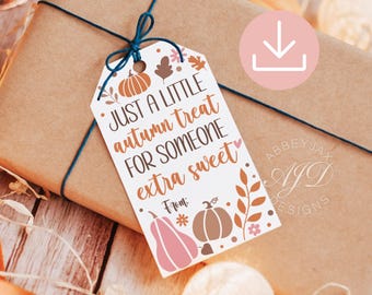 May include: A white rectangular gift tag with a dark blue string, featuring orange and pink pumpkin illustrations, autumn leaves, and the text: Just a little autumn treat for someone extra sweet. From: with space for a name, on a brown package.