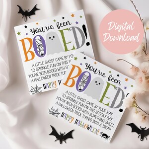 May include: Two square white cards featuring the text You've been BOOED! with a ghost, spiderweb, and colorful lettering. The cards include the poem A little ghost came by your way, to sprinkle fun on this spooky day. You've been booed with something sweet, a Halloween trick turned into a treat! Happy Halloween.