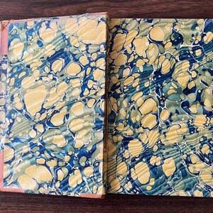 May include: Close-up of the marbled paper cover of a book. The cover is a mix of blue, green, and yellow swirls.
