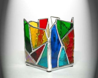 May include: A colorful stained glass candle holder with a geometric design. The holder is made of glass and metal and features a variety of colors, including red, yellow, green, blue, and purple.
