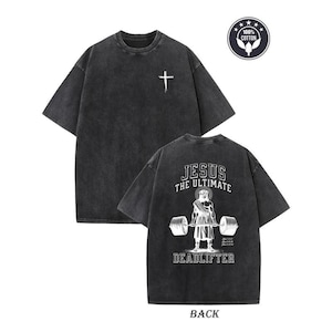 a black t-shirt with a graphic design on the back, depicting a person lifting weights and the text "JESUS THE ULTIMATE DEADLIFTER" printed on it.