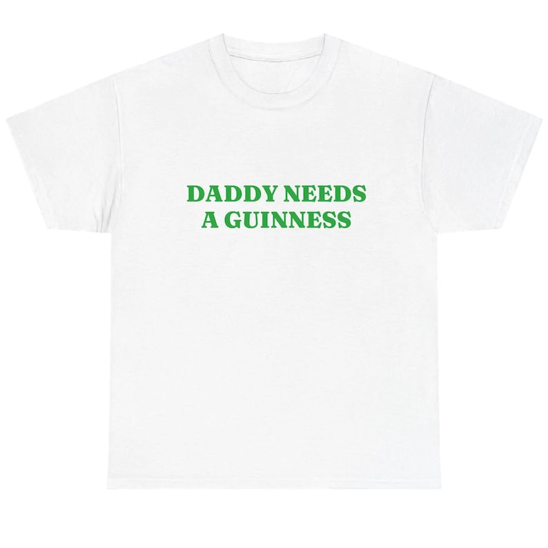 May include: White t-shirt with the green text "DADDY NEEDS A GUINNESS" across the chest. The shirt is a casual, crew neck style, suitable for everyday wear. The text is in a bold, sans-serif font.