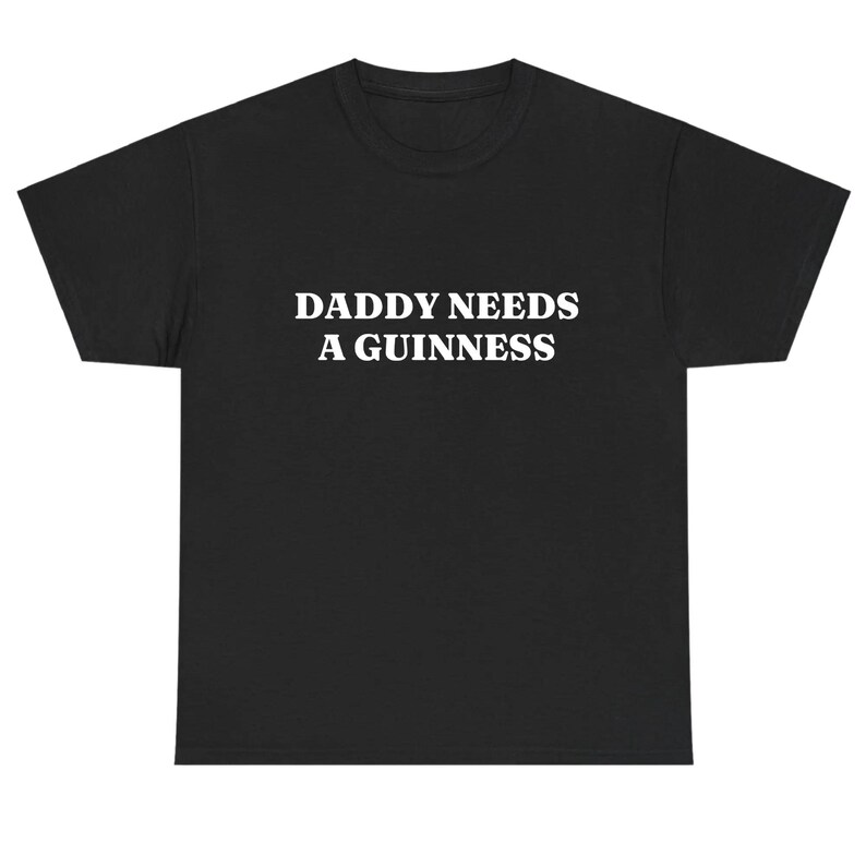 May include: Black t-shirt with the white text "DADDY NEEDS A GUINNESS" across the chest. The shirt is a basic crew neck style, suitable for casual wear. The text is centered and in a bold, sans-serif font.