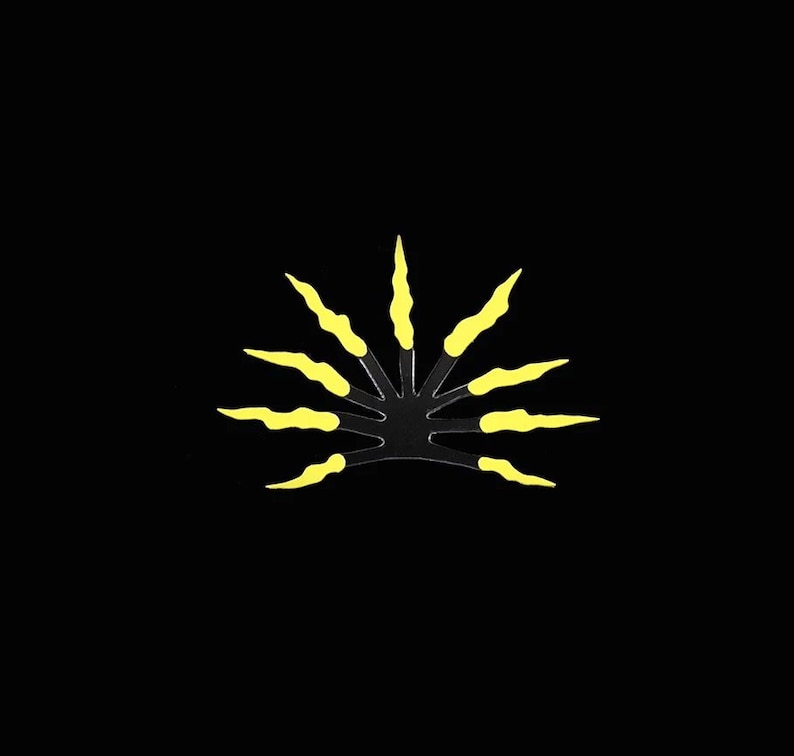 May include: A black hair comb with yellow teeth. The comb is shaped like a sun with 12 teeth.