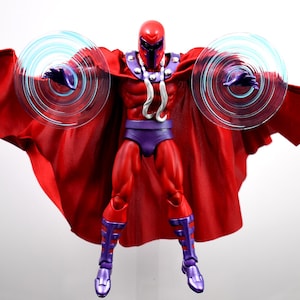 May include: A red action figure of Magneto, a comic book character, with a red cape and helmet. The figure is posed with arms outstretched, and translucent blue energy discs emanate from each hand. The figure wears purple trunks and boots.