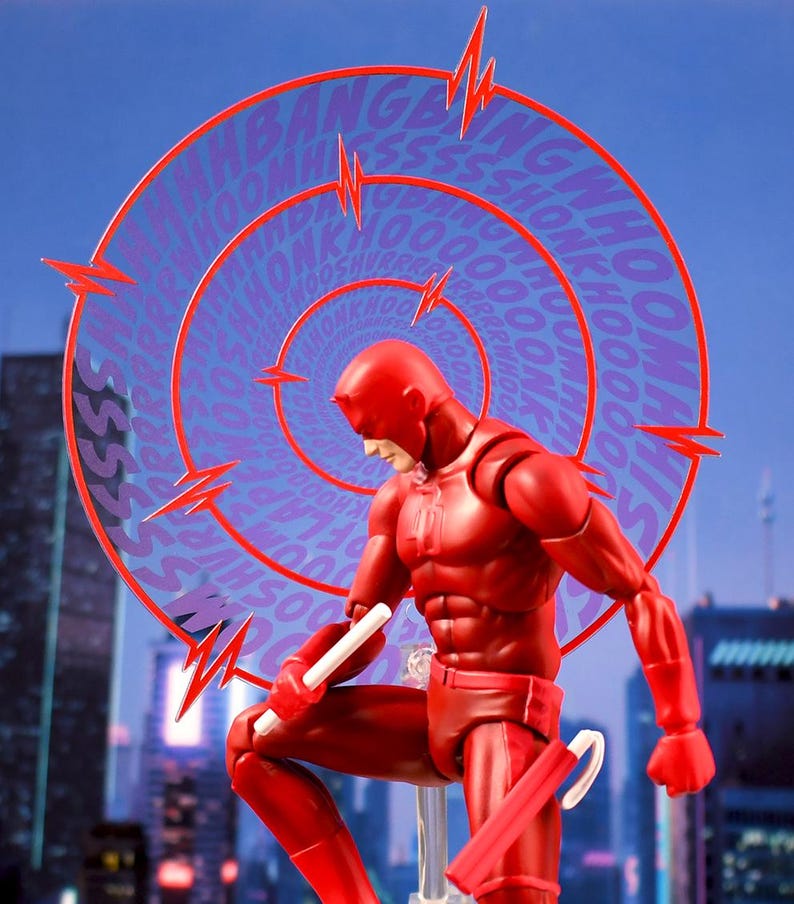 K&ouml;nnte beinhalten: Eine rote Actionfigur von Daredevil, einem Superhelden, der f&uuml;r seine &uuml;bermenschlichen Sinne bekannt ist, ist in einer dynamischen Pose dargestellt. Er h&auml;lt einen wei&szlig;en Stock in seiner rechten Hand und einen roten Schlagstock in seiner linken Hand. Die Figur ist vor dem Hintergrund einer Skyline einer Stadt mit einem lila und roten Comic-Soundeffekt-Grafik hinter ihm platziert.