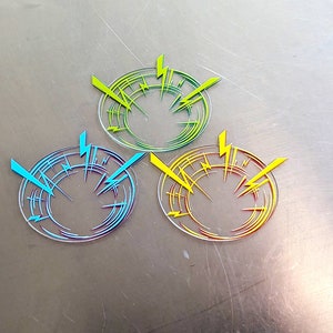 May include: Three circular stickers with a lightning bolt design. The stickers are transparent with yellow, blue, and red lightning bolts.
