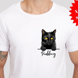 Peut inclure: T-shirt blanc avec un chat noir qui regarde par-dessus le haut du t-shirt. Le chat a les yeux jaunes et le texte "Pudding" est imprimé sous le chat.