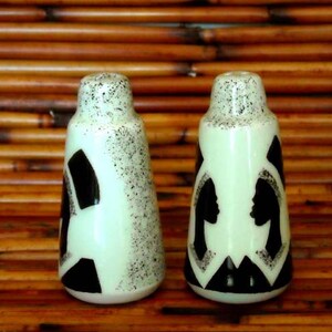 以下が含まれることがあります： 白黒のシルエットデザインが施されたセラミック製の塩コショウ入れ2個セット。塩コショウ入れは白で斑点があり、薄い緑色の釉薬がかかっています。