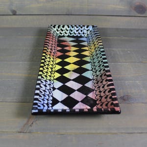 May include: A rectangular serving tray with a black and white checkered pattern and a rainbow colored border. The tray is made of ceramic and has a glossy finish.