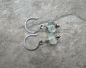 May include: A pair of silver earrings with light green gemstone beads. The earrings have a simple wire design and are perfect for everyday wear.
