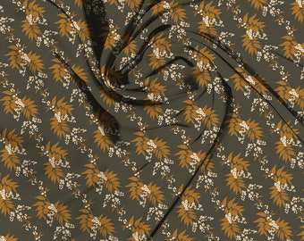 May include: Dark olive green fabric with a repeating pattern of stylized golden-brown leaves and small white flower clusters. The fabric is draped, creating shadows and highlighting the design's texture and flow.